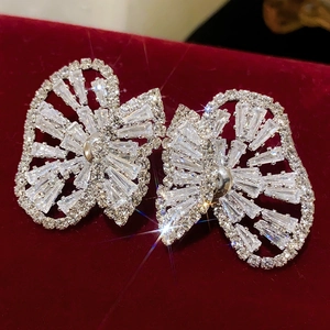 Close-up of sparkling bow earrings with rhinestones on a red velvet background