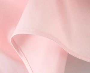 Close-up of pink elegant dress showing smooth fabric texture and precise stitching detail