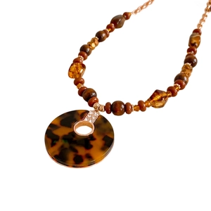 Collier en perles de bois léopard avec pendentif en strass brillant sur fond blanc