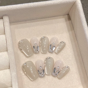 Detail of handmade cat-eye press-on nails with rhinestones in a velvet jewelry box