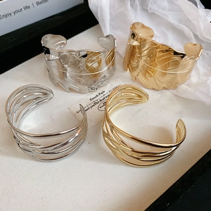 Detail of gold and silver irregular leaf-pattern and multi-layer wrap open bangles