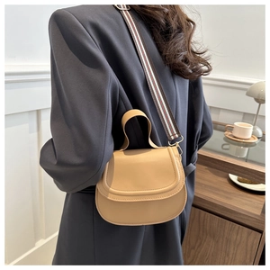 Khaki saddle bag with red-green striped strap styled with a grey blazer on model