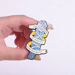 Enamel lapel pin with sage bundle design and humorous quote on a hand-held display