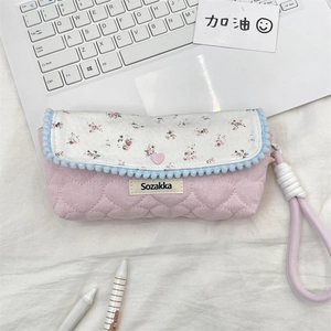 Detailed view of pink quilted floral pencil case with heart stitching and pom-pom trim