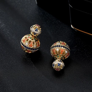 Macro shot of gold double-sphere earrings with colorful zircon stones on black background