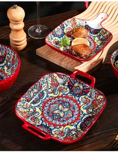 Detail of red Bohemian ceramic baking dish with handles on dark wood dining table