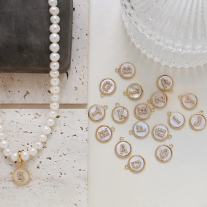Detailed view of gold-plated alphabet charms with zircon and pearl necklace on a display