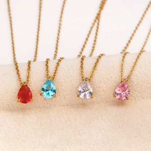Close-up of teardrop zircon pendants in four colors on a gold chain necklace