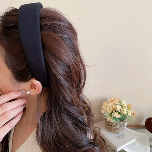 Close-up of a black padded headband showing thick fabric texture and elegant velvet design