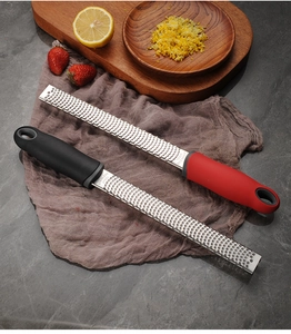 Detail of stainless steel zester graters with black and red handles on grey linen cloth