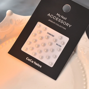 Macro shot of 5D gold-stamped pearl nail art charms on black card for jewelry collection