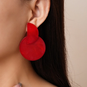Close-up of red geometric resin hoop earrings worn by a model in a professional shot
