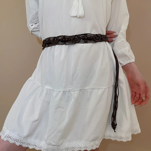 Detail of bohemian dark brown woven waist chain with wood beads and tassel on white dress
