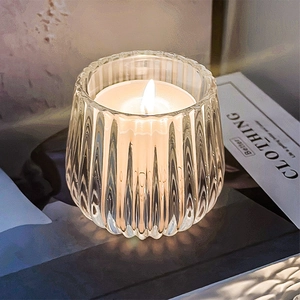 Elegant vertical fluted glass candle holder with burning white paraffin wax for home decor