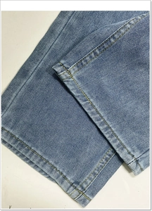 Detailopname van de lichtblauwe denim zoom met gele versterkte stiksels en kepertextuur