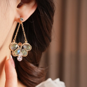 Close-up of vintage butterfly drop earrings with colorful gemstones worn by a model