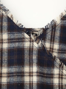 Close-up of V-neckline with frayed fringe edges on blue and brown plaid tweed dress