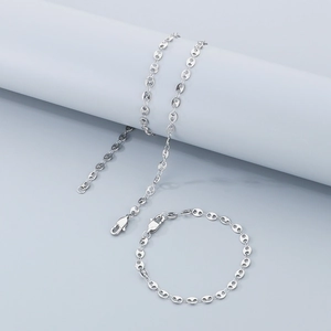 Detailed view of silver coffee bean link necklace and bracelet set on geometric props