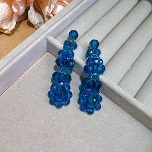 Detail of blue crystal tassel earrings showcased in a grey velvet jewelry box with flowers