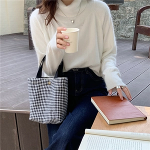 Close-up of black and white houndstooth wool tote bag with golden magnetic snap closure