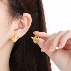Detailed view of golden seashell stud earrings worn by a model for a chic ocean style