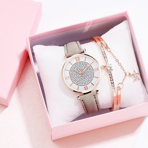 Detail van roségouden horlogeset met sterarmband en grijze band in een geschenkdoos