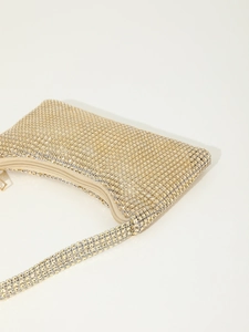Close-up of golden rhinestone evening bag with sparkling crystals and metal zipper detail