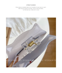 Detailed close-up of a translucent acrylic cat hair claw clip with a durable gold metal spring