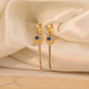 Detailed close-up of gold tassel earrings with evil eye bead and sparkling rhinestones
