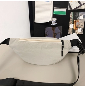 Close-up of cream crescent chest bag made of durable nylon with black zipper detail