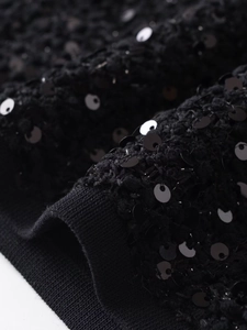 Dettaglio macro del tessuto con paillettes nere con trama a maglia e bordo della giacca