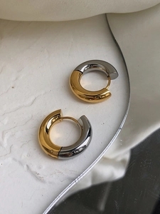 Close-up of gold and silver two-tone polished thick hoop earrings on a white tray