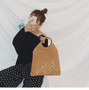 Detail of hand-woven cotton rope bag featuring round wooden handles and hollow mesh texture