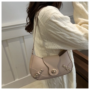 Chic beige shoulder bag with gold turn-lock and rivets worn with white knit sweater