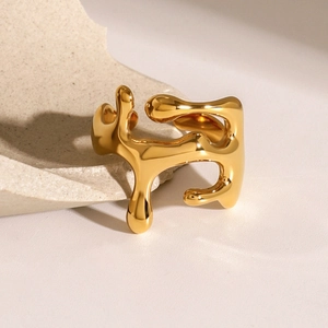 Minimalist gold liquid metal ring with abstract melted texture on a stone pedestal