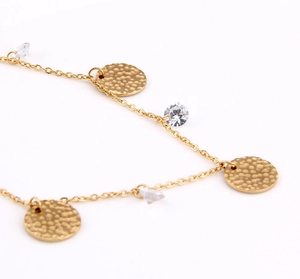 Macro detail of gold-plated cable chain with hammered metal discs and faceted crystals