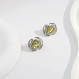 Detail of fan-shaped silver stud earrings featuring smooth yellow-green cat eye stones
