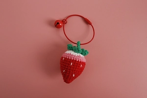 Close-up of handmade crochet strawberry keychain with red bell and pink leaf detail