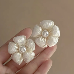 Detail of vintage flower tassel earrings with central pearl shown in hand