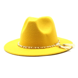 Detail of yellow wool fedora hat featuring gold chain link, pearls and tassels fringe