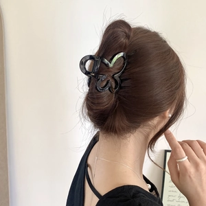 Detail view of a minimalist black butterfly hair claw clip styled on a woman's hair