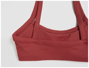 Détail des coutures renforcées et de la bordure du soutien-gorge de sport rouge bordeaux