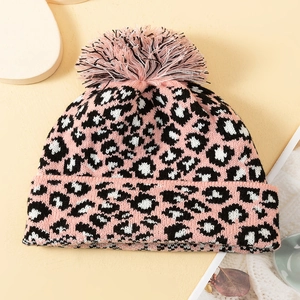 Detailed view of leopard print knit hat with pink and white faux fur pompom texture