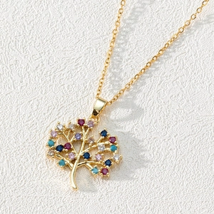 Close-up of 18K gold tree of life pendant with colorful zircons on white leather