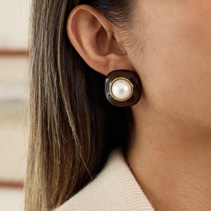 Gros plan sur une boucle d'oreille vintage en perle, résine brune et bordure dorée