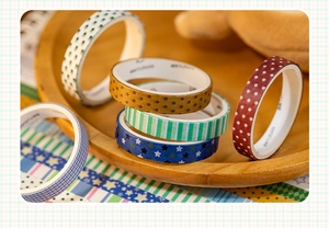 Makro-Detail von verschiedenen Retro-Washi-Tape-Rollen mit Sternen auf Holztablett