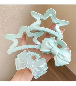 Set of four light blue cream style star and bow hair claws held by hand for elegant hair styling