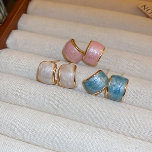 Detail of candy-colored C-shaped earrings in pink, pearl white and sky blue hues