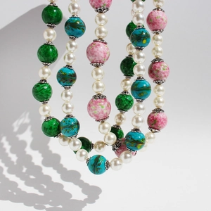 Exaggerated multi-strand pearl necklace with colorful pink and green beads on white