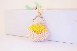 Detail of a handbag-shaped keychain with gold alloy, yellow rhinestones and pearls